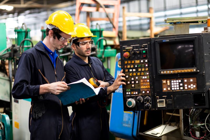 Curto circuito, o que é: trabalhadores avaliando problema elétrico em máquina industrial.